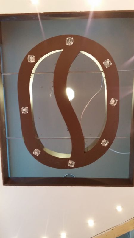 Custom illuminated coffee bean sign ceiling feature during installation
