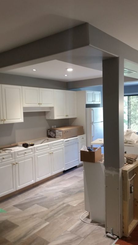 Finished open concept kitchen dining and living room with boxed beam and new cabinetry