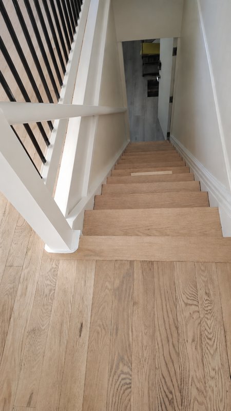 Staircase before renovation — light oak unfinished stairs